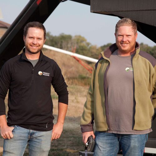 Govier Farms team members standing beside farm equipment